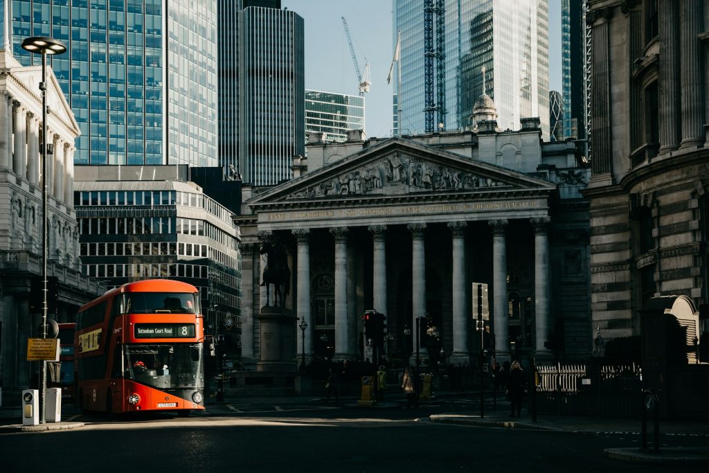 The Royal Exchange in the City of London with modern towers and a red bus