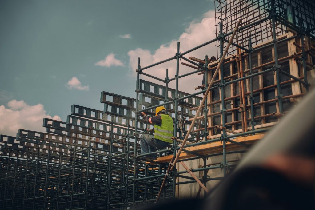 A worker in high-visibility clothing on scaffolding at a construction site, representing liability insurance